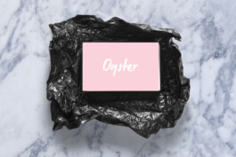 business card with the brand logo places in a black plastic packaging and lying on a marble surface. 